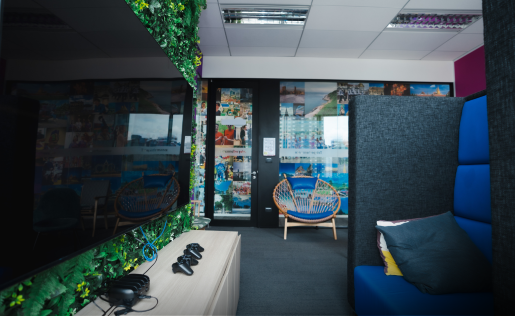 A vibrant, modern office lounge with gaming gear and cozy seating