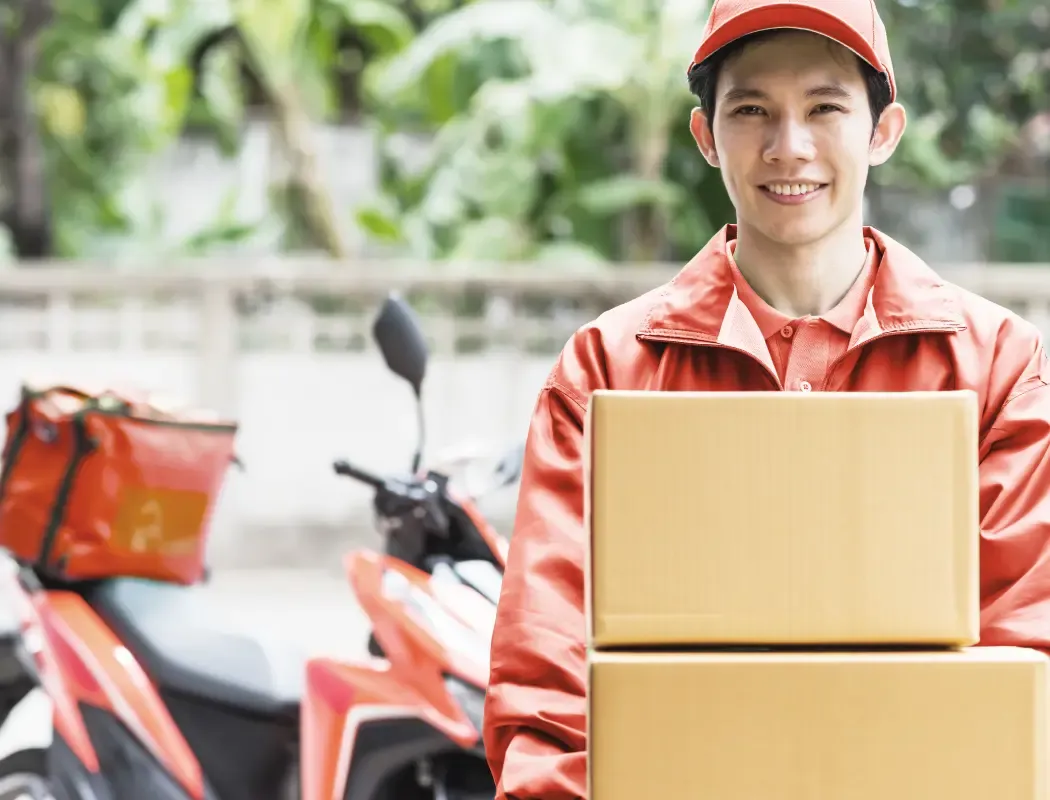 Delivery worker in an orange uniform delivering packages to their destination.