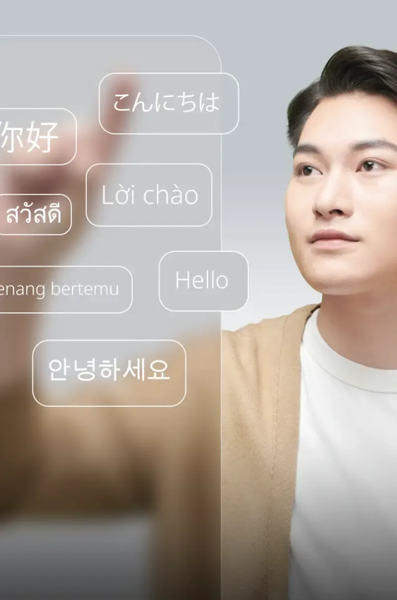 ชายหนุ่มชาวเอเชียโต้ตอบกับอินเทอร์เฟซหลายภาษาแบบ 3 มิติ สื่อถึงการเชื่อมโยงระดับโลก