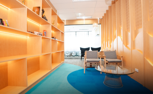 A warm modern office lounge with wooden shelves and cozy seating.