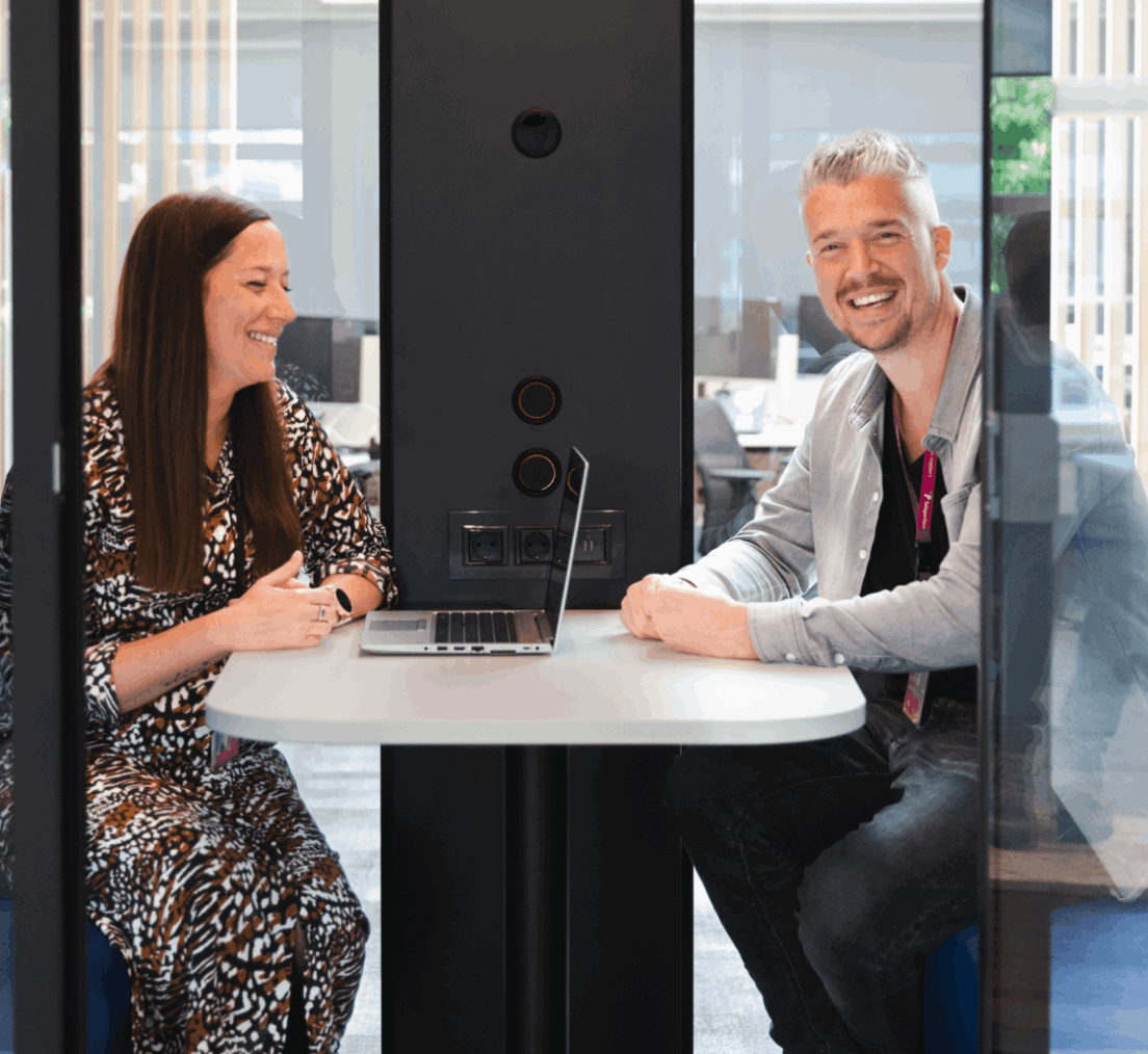 Two colleagues discussing work at a desk in a modern office at TP.